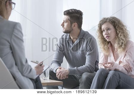 Young married couple talking to psychiatrist on therapy session