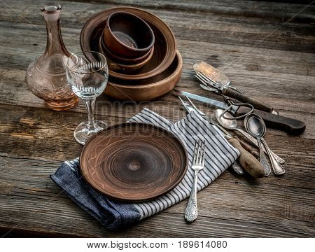 Rusic dishware sitting on the table, nice glass bottle and blue cotton napkin