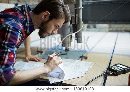 Serious engineer looking through papers with technical sketches