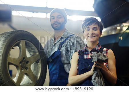 Young female technician looking at camera with her mentor behind