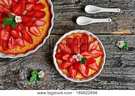 cheesecake with strawberries and fresh flowers, strawberries on a wooden table - right side view