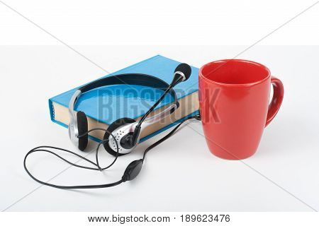 Audiobook on white background. Headphones put over blue hardback book, empty cover, copy space for ad text. Distance education, e-learning concept
