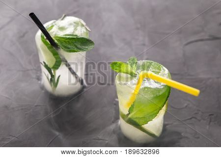 two glasses with fresh cocktail made of ice on concrete table. concept