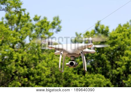 KAGAWA, JAPAN - MAY 20, 2017: White remote controlled Drone Dji Phantom4 Pro equipped with high resolution video camera flying in air and blue sky in the forest