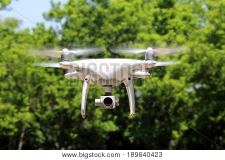 KAGAWA, JAPAN - MAY 20, 2017: White remote controlled Drone Dji Phantom4 Pro equipped with high resolution video camera flying in air and in the forest