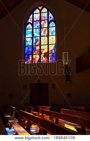 Modern Stained Glass Windows Reflecting Colors On Church Pews