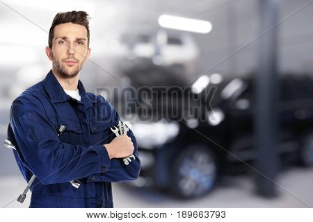 Auto mechanic with tools and workshop on background. Car service concept