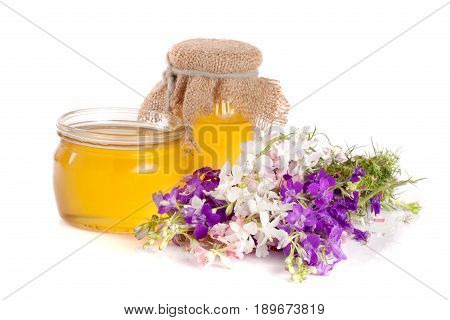 Jar of honey with wildflowers isolated on white background.