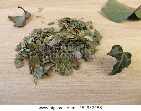 Dried ivy leaves, Hedera folium, on wooden board