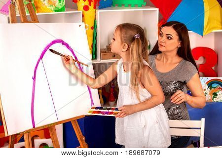 Children painting finger on easel. Group of kids girl and boy with teacher learn paint in class school. Child picture on background. Students draw a rainbow.