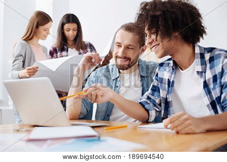This will work for us. Charming creative talented man using a gadget for showing a presentation to his colleague and asking for his opinion