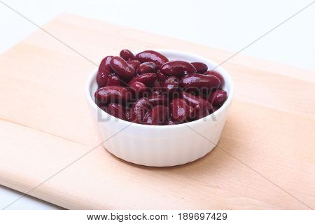 Heap of canned red kidney beans in the sauce in white bowl. vegetarian food. Phaseolus vulgaris
