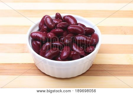 Heap of canned red kidney beans in the sauce in white bowl. vegetarian food. Phaseolus vulgaris