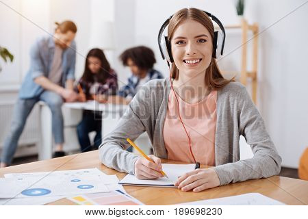 Development through additional studying. Gorgeous elegant enthusiastic woman wearing headphones and listening some informative tracks while trying understanding new subject