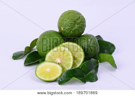 Whole and slices of Kaffir limes with leaves.  Also known as Limau Purut in Malaysia.  Have strong citrus fragrance and used in asian cuisine.  White background.