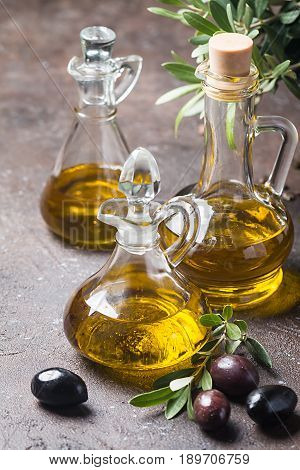 Olive oil in a glass bottle and olive branch on brown stone table