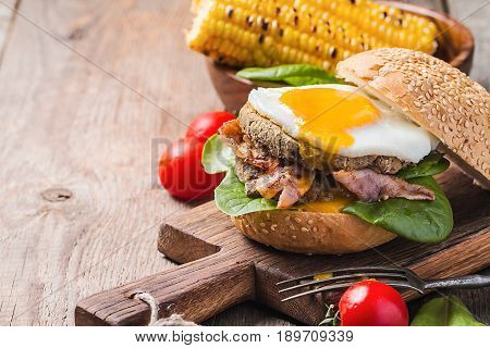Homemmade Bacon Hamburger with fried Egg, Lettuce and lentil burger with a garnish of corn and tomatoes