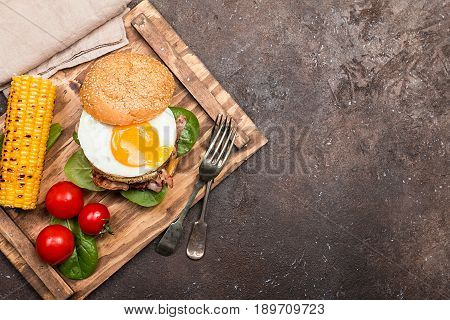 Homemmade Bacon Hamburger with fried Egg, Lettuce and lentil burger with a garnish of corn and tomatoes, top view