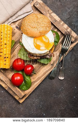 Homemmade Bacon Hamburger with fried Egg, Lettuce and lentil burger with a garnish of corn and tomatoes, top view