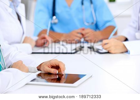 Group of doctors at medical meeting. Close up of physician using tablet computer