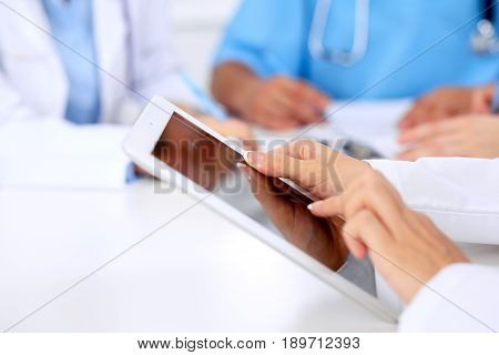 Group of doctors at medical meeting. Close up of physician using tablet computer