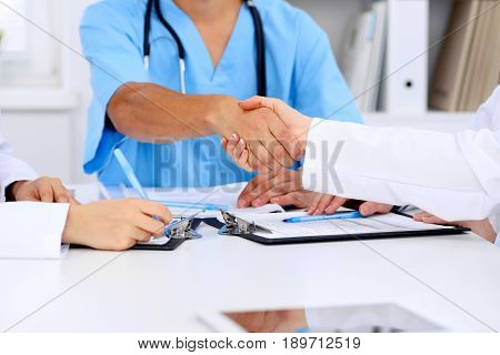 Doctors shaking hands to each other finishing up medical meeting.