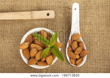 Almonds In White Ceramic Bowl On Sack Background