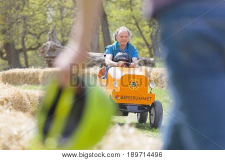 STOCKHOLM SWEDEN - MAY 21 2017: Smiling boy and granpa driving a orange soapbox car downhill on a field in the race Gardesloppet at Djurgarden Stockholm Sweden. May 21 2017