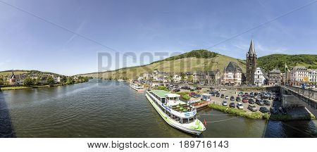 People Enjoy The River Cruise On River Moselle With View To Old Historic Town Of Bernkastel-kues