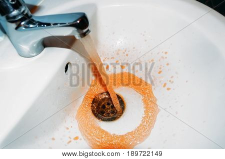 Rust flowing from the tap in the bathroom. Concept of the problem is dirty water