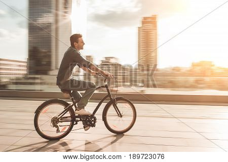 Young stylish man is cycling in the city on the sunset