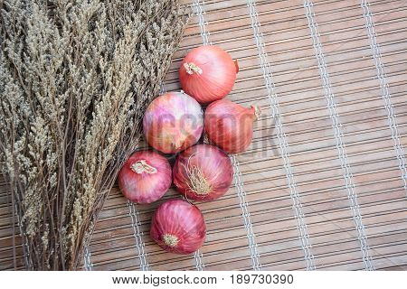 large Bombay red onion with dried flowers on a vintage bamboo matt.