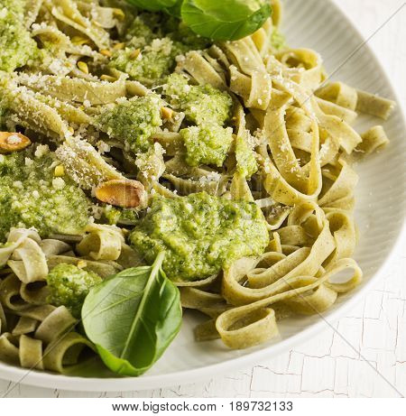 Tasty appetizing italian pasta with sauce pesto and pistachios on white plate. Closeup.