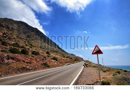 Warning sign in a red triangle on a mountain road