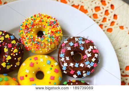 Yellow and brown donuts on a white plate