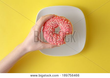 Ring Donut With Pastel Frosting And Sprinkles On A Bright Yellow Background, With A Bite Missing