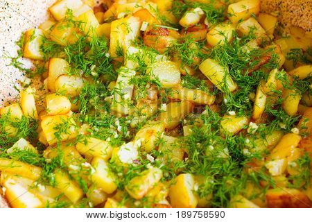 Fried potatoes in a frying pan close up. Kortofel fried in a frying pan and sprinkled with dill and garlic.