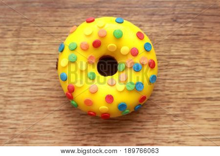Single yellow donut on a wood background