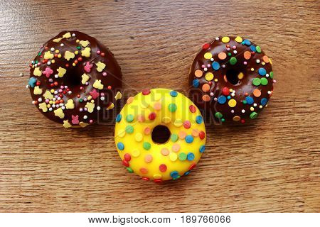 Three assorted donuts on a wood background