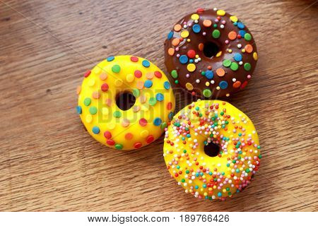 Three assorted donuts on a wood background