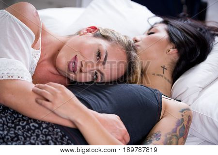 Sexy lesbians lovers in bed at morning, blonde girl is sleeping over the brunette girl chest, in a white background.