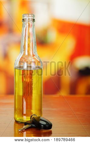 Close up of a botlle of beer with car keys on wooden table.