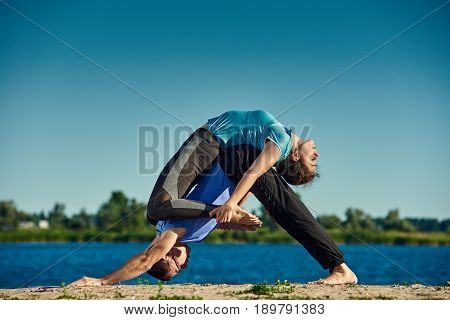 Fit young couple doing acro yoga outdoors