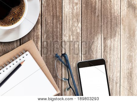 Top view cup of coffeesmart phoneglassespencil and notebook on wooden table with copy space