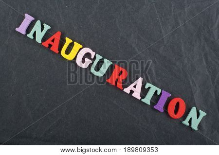 Iinauguration . English word on black board background composed from colorful abc alphabet block wooden letters, copy space for ad text. Learning english concept