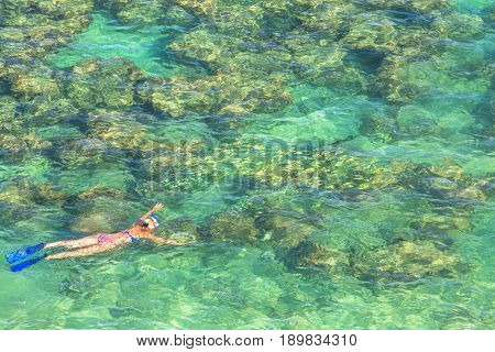 Woman snorkeling over coral reef in famous Hanauma Bay Nature Preserve, Oahu island, Hawaii, USA. Female snorkeler swims in tropical sea with american flag bikini. Watersport activity in Hawaii.