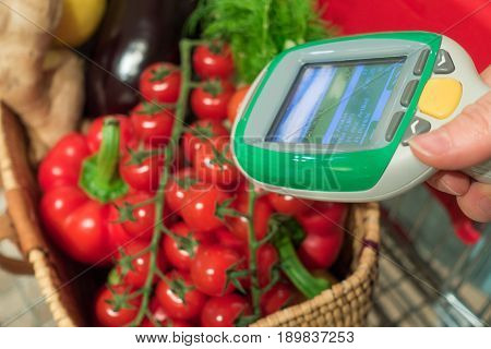 Woman customer using handheld scanner device in supermarket. Automatic object recognition of vegetables. The future of grocery shopping.