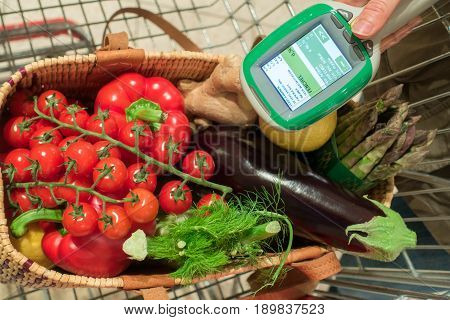 Woman customer using handheld scanner device in supermarket. Automatic object recognition of vegetables. The future of grocery shopping.