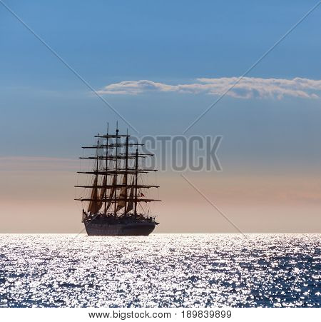 The world's largest sailing ship with five masts leaves at sunset in the open sea.