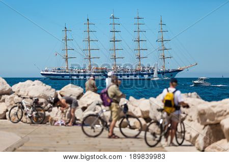 The world's largest sailing ship with five masts anchored in the open sea near old city Piran Slovenia. Tourists on bicycles are looking at the beautiful ship.